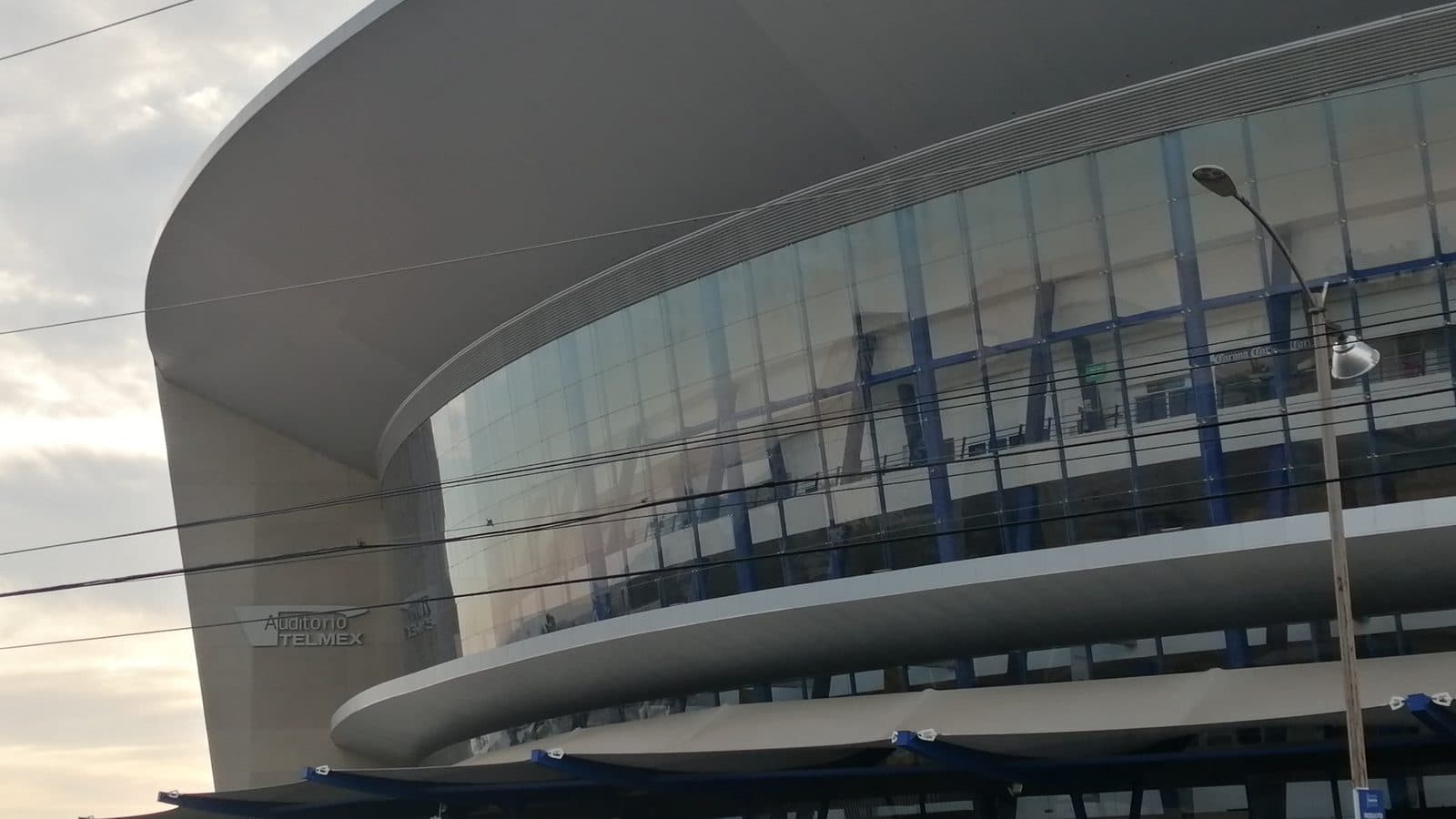 Fachada curva del Auditorio Telmex en Zapopan: una gran cubierta blanca sobre el muro de vidrio del vestíbulo.