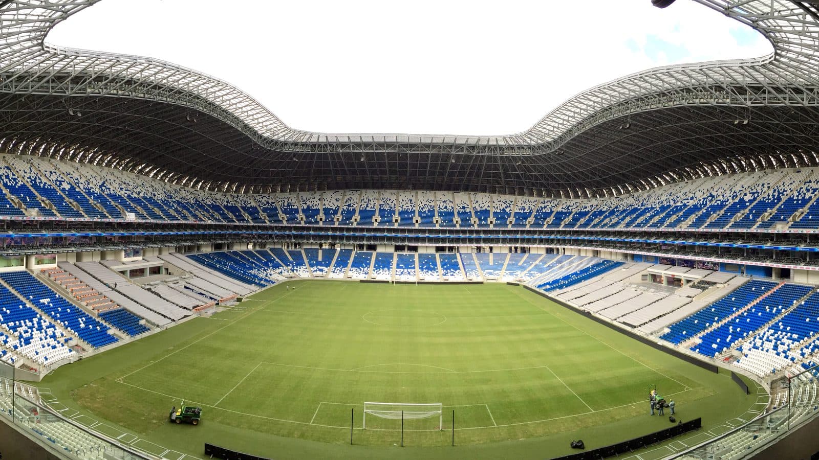 Interior del Estadio BBVA: la cancha de futbol rodeada de tribunas con butacas azules y blancas bajo la cubierta.